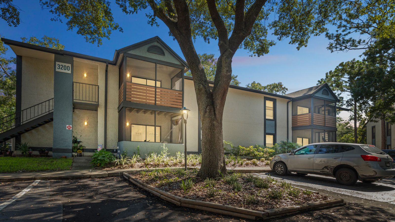the exterior of an apartment complex with trees and cars parked in front at The Vista Bay